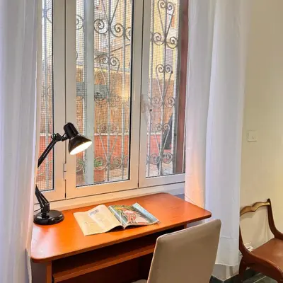 a desk with a lamp and a book next to a window at Bella Roma Stay in Rome
