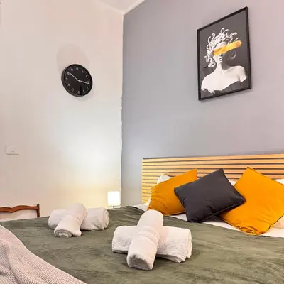 a bed with towels on it with a clock on the wall at Bella Roma Stay in Rome