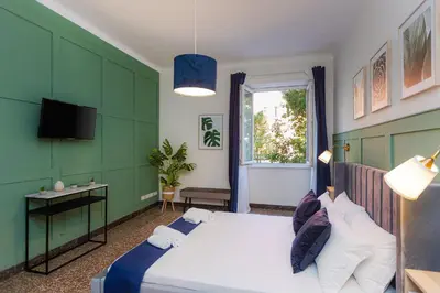a bedroom with a bed and a desk and a window at Vatican Flower Apartment in Rome