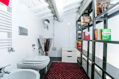 a bathroom with a toilet and a book shelf at Trastevere Design Loft - My Extra Home in Rome