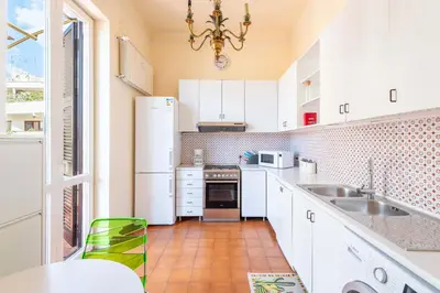 a white kitchen with a sink and a refrigerator at Coppede' Penthouse in Rome