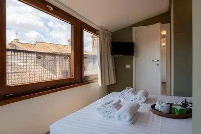 a bedroom with a bed with towels and a window at SKY DOMUS ROME Historic Center Penthouse With Jacuzzi in Rome