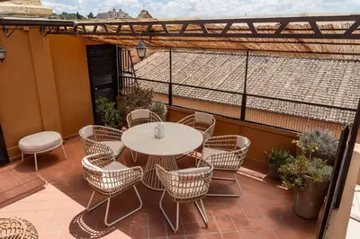 a patio with a table and chairs on a balcony at SKY DOMUS ROME Historic Center Penthouse With Jacuzzi in Rome