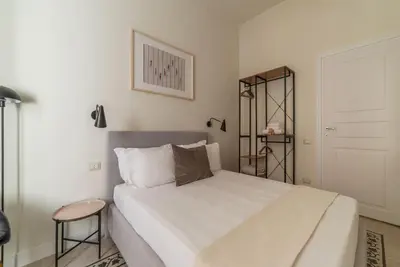 a bedroom with a large white bed and a stool at Casa Enea - Pretty Homes in Rome