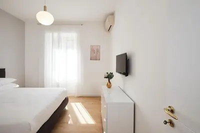 a white bedroom with a bed and a tv at 20 Minuti Vaticano - Nido Romano Shopping Folkoristico by Hôtea in Rome