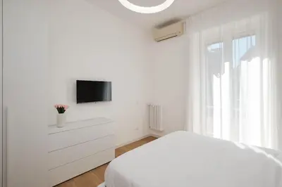 a white bedroom with a bed and a tv at 20 Minuti Vaticano - Nido Romano Shopping Folkoristico by Hôtea in Rome