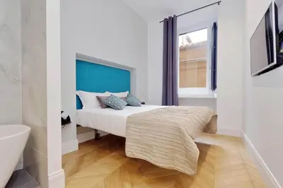 a bedroom with a bed with a blue headboard and a window at EVE Guest House at Trevi Fountain in Rome