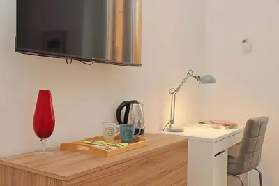 a desk with a tv on a wall with a lamp and a chair at Prestigious Re di Roma Apartment in Rome