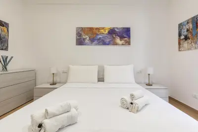 a white bedroom with a white bed and two chairs at Hostly-Libia Light Lodge-10min Metro to Colosseum in Rome