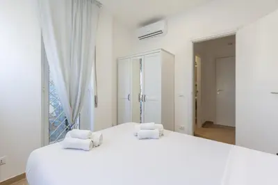 a white bedroom with two white towels on a bed at Hostly-Libia Light Lodge-10min Metro to Colosseum in Rome