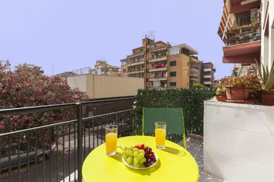a yellow table with a bowl of fruit on a balcony at Hostly-Libia Light Lodge-10min Metro to Colosseum in Rome