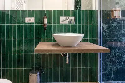 a green tiled bathroom with a white bowl on a counter at Flat 285 La Suite in Rome