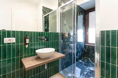 a green tiled bathroom with a sink and a shower at Flat 285 La Suite in Rome