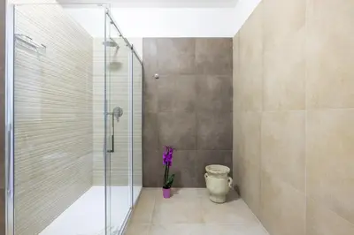 a bathroom with a shower and a vase with purple flowers at Angela luxury home,Premium Apartment for families in Rome