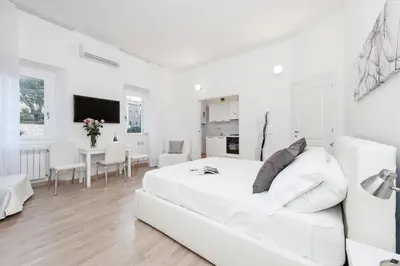 a white bedroom with a white bed and a dining room at White Flat Colosseo in Rome