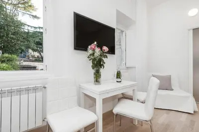 a white room with a table and two chairs and a tv at White Flat Colosseo in Rome