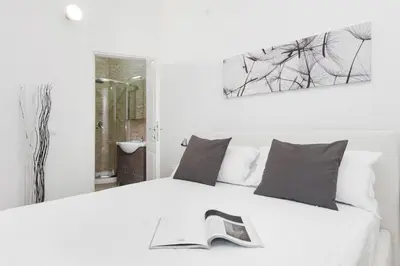 a bedroom with a white bed with a book on it at White Flat Colosseo in Rome