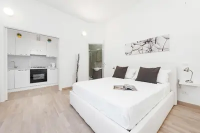 a white living room with a white couch and a kitchen at White Flat Colosseo in Rome