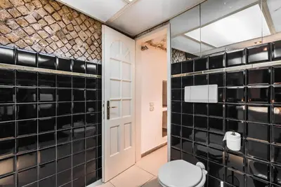a bathroom with black tiled walls and a toilet at Colosseum Townhouse in Rome