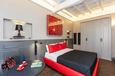 a bedroom with a bed with red pillows and a table at Amazing Piazza di Spagna in Rome