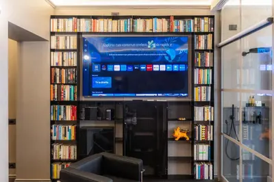 a living room with a tv and book shelves with dvds at Amazing Piazza di Spagna in Rome