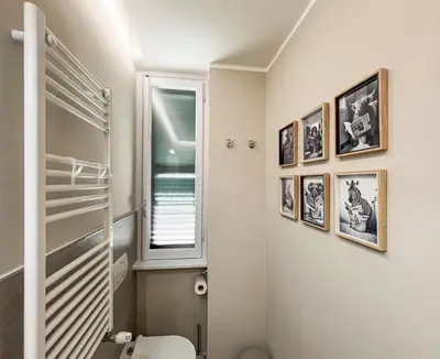 a bathroom with a toilet and pictures on the wall at Attico Urbano Terrazza su Roma Metro A Cornelia in Rome