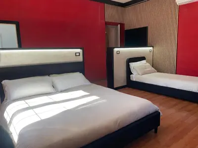 a bedroom with two beds and a red wall at La Villa di Roma in Rome