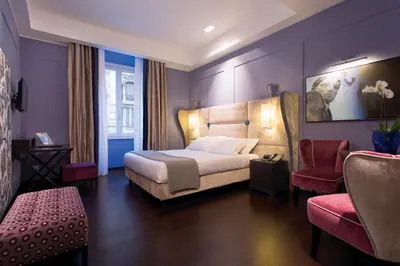 a hotel room with a bed and a chair at Stendhal Luxury Suites in Rome