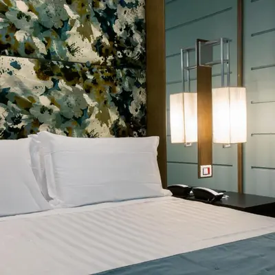 a bed with white pillows and a table with a lamp at Stendhal Luxury Suites in Rome