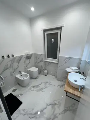 a marble bathroom with a sink and a toilet at Alba White in Rome