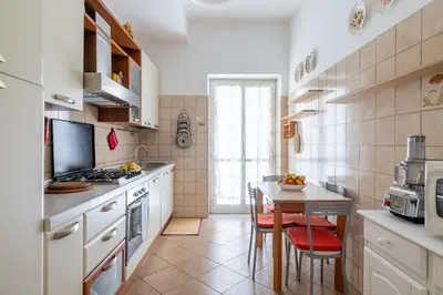 a kitchen with white cabinets and a small table with chairs at Aurelia Dream with Terrace in Rome