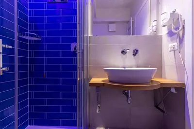 a bathroom with a sink and a shower with blue tiles at Dafne room Speciale, elegante con balcone in Rome