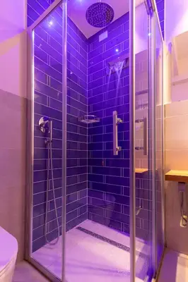 a bathroom with a shower with blue tiles at Dafne room Speciale, elegante con balcone in Rome