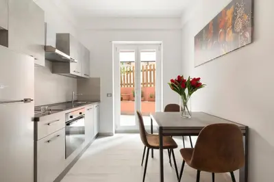 a kitchen with a table with chairs and a vase of flowers at Ginny in Trastevere in Rome
