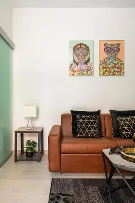 a living room with a brown couch and paintings on the wall at Ginny in Trastevere in Rome