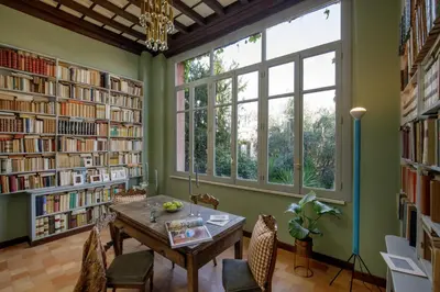 a library with a table and chairs and large windows at Daplace - Villetta Sant'Onofrio in Rome