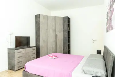 a bedroom with a pink bed and a tv at Rea house Colli Albani - B&Brother's rome in Rome