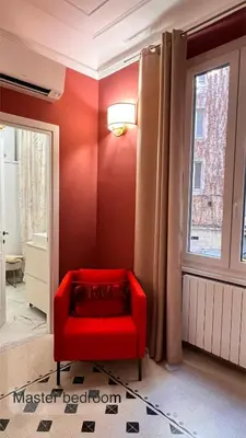 a red chair in a room with a window at 3Bdr Apartment in the heart of Rome in Rome