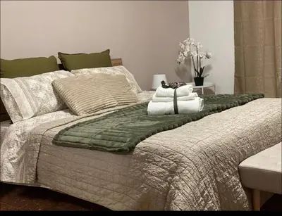 a large bed with a green blanket and pillows at Fuffy House Rome in Rome