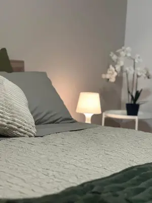 a bed with a pillow and a table with a lamp at Fuffy House Rome in Rome