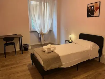 a bedroom with a bed and a desk and a window at PiazzaBolognaStay in Rome