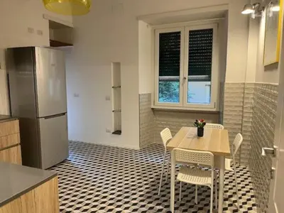 a kitchen with a table and chairs and a refrigerator at PiazzaBolognaStay in Rome