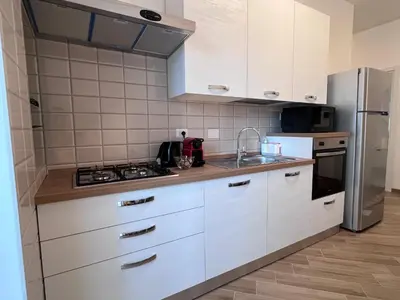 a kitchen with white cabinets and a stainless steel refrigerator at Dasy Apartment - San Paolo in Rome