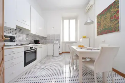 a kitchen with white cabinets and a white table and chairs at Appartamento 