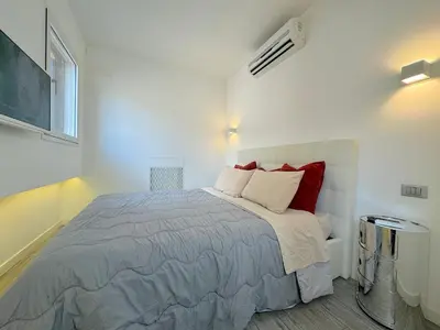 a white bedroom with a large bed with red pillows at Mercede Apartment - Spanish Steps in Rome