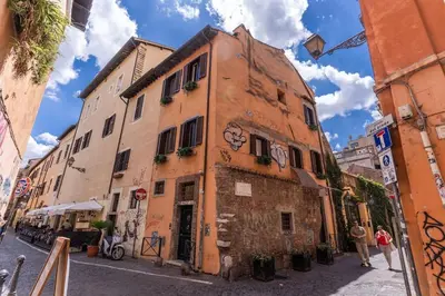 an orange building with a clock on it on a street at Piazza dei Renzi Trastevere building 4 bedroom with terrace in Rome