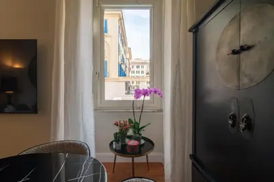 a table with flowers on it next to a window at Villa Borghese Luxury Place in Rome