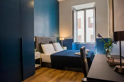 a blue bedroom with a bed and a window at La Trasteverina apartment in Rome