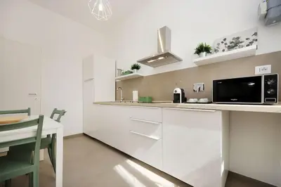 a kitchen with white cabinets and a black microwave at Basilica San Paolo Nuvola EUR Modern apartment in Rome
