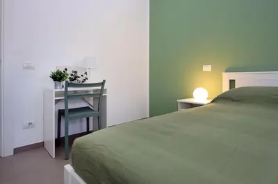 a bedroom with a bed and a desk and a chair at Basilica San Paolo Nuvola EUR Modern apartment in Rome